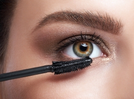 Close-up of young woman applying mascara on eyelashes by cosmeti